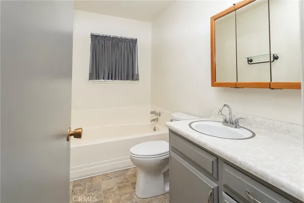 a bathroom with a granite countertop sink toilet a mirror and bathtub
