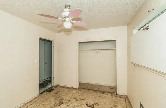 an empty room with a window and a ceiling fan