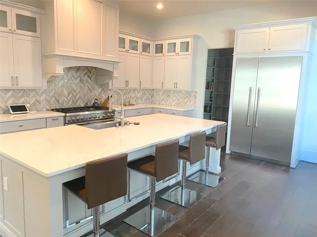 a kitchen with stainless steel appliances granite countertop a sink a microwave a refrigerator and white cabinets