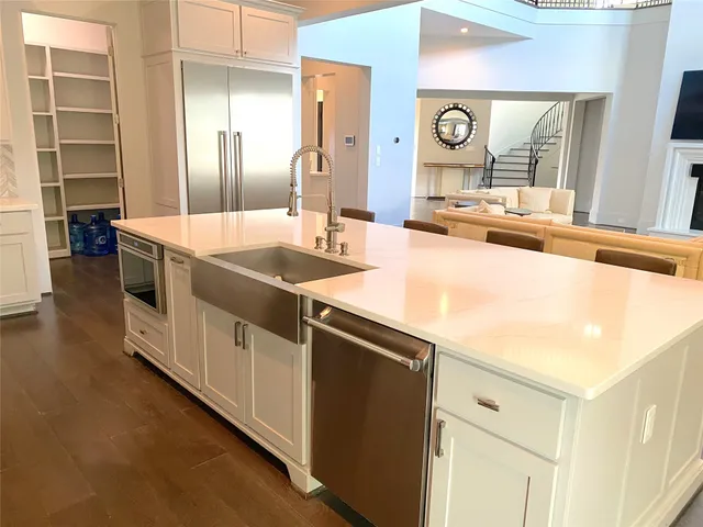 a large kitchen with stainless steel appliances a large counter top a stove and a refrigerator