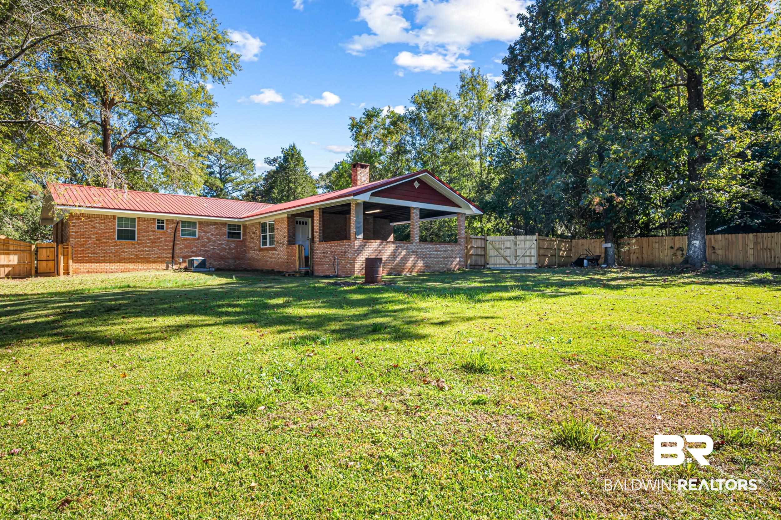 1605 Collier Avenue Bay Minette, AL 36507 - Photo 34 of 36 Rear view of property with a fenced backyard, brick siding, a chimney, and a metal roof