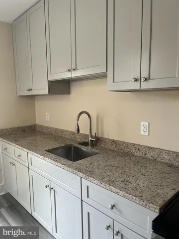 a kitchen with granite countertop white cabinets and sink