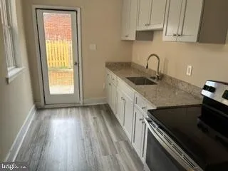 a kitchen with granite countertop a stove a sink and dishwasher with wooden floor