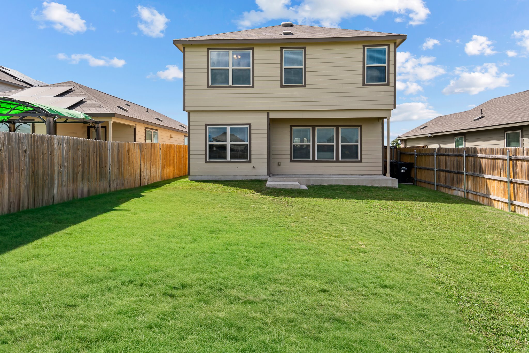 576 Greatest Gift Way Jarrell, TX 76537 - Photo 33 of 37 A spacious, verdant yard extends behind a two-story residence with well-maintained siding.