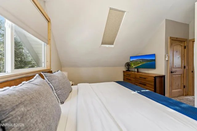 a bedroom with a bed and a flat tv screen on dresser