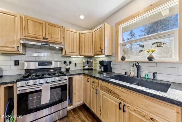 a kitchen with stainless steel appliances granite countertop a sink a stove and cabinets