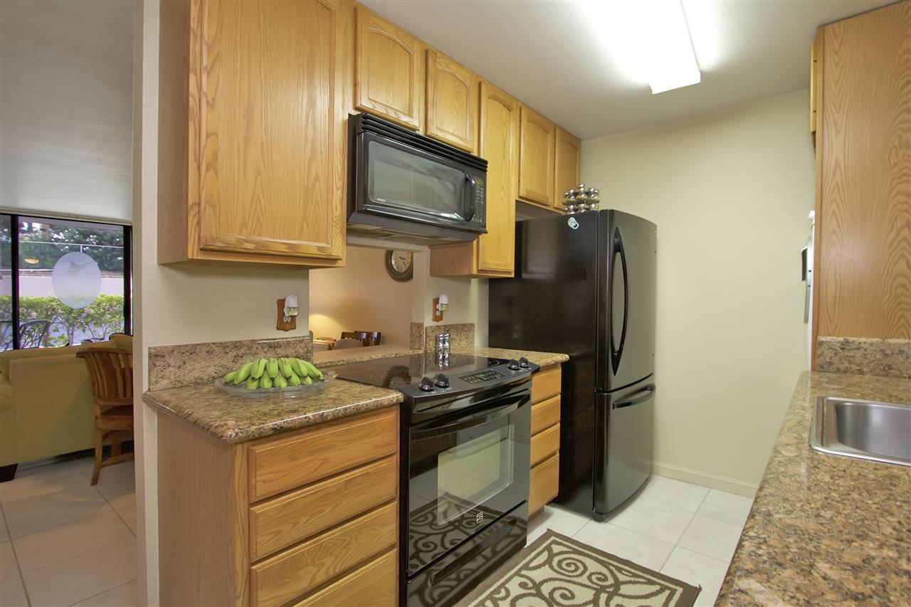 2219 South Kihei Road, Unit B102 Kihei, HI 96753 - Photo 9 of 30 a kitchen with stainless steel appliances granite countertop a refrigerator stove and microwave