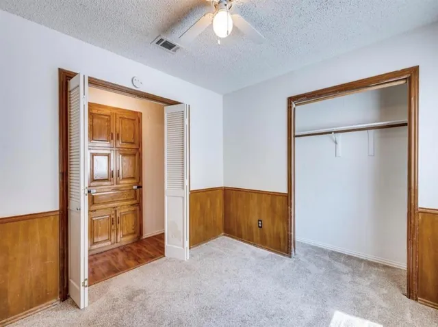 an empty room with closet and a chandelier fan