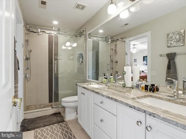 a bathroom with a shower sink vanity mirror and toilet