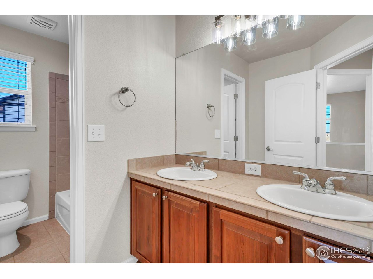 1936 Alpine Drive Erie, CO 80516 - Photo 31 of 47 a bathroom with a granite countertop sink a toilet a mirror and shower