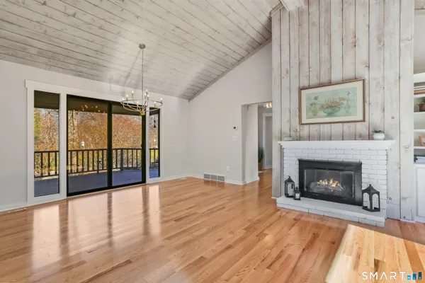 a view of an empty room with wooden floor fireplace and a window