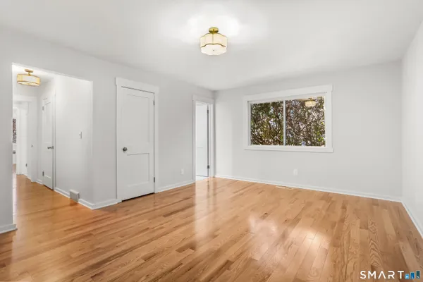 an empty room with wooden floor and ceiling fan