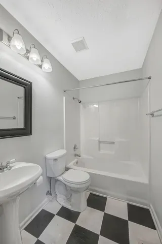 a bathroom with a sink a toilet a mirror and shower