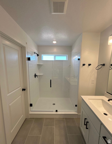 2818 West Aurora Avenue Mapleton, UT 84664 - Photo 7 of 9 Bathroom with a stall shower, vanity, dark tile patterned floors, and a textured ceiling