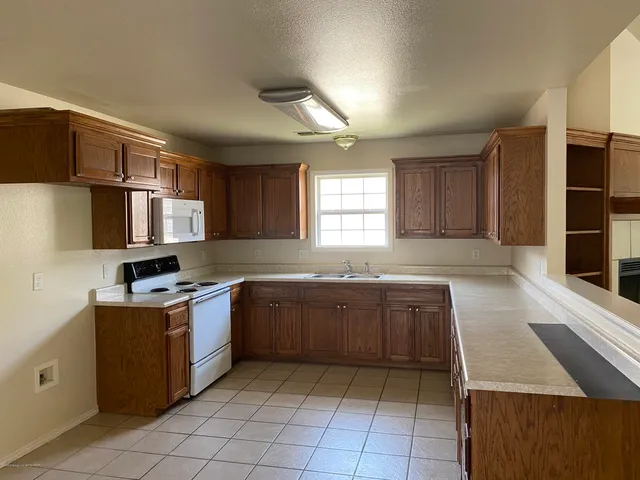 a kitchen with stainless steel appliances granite countertop a stove top oven a sink and a refrigerator