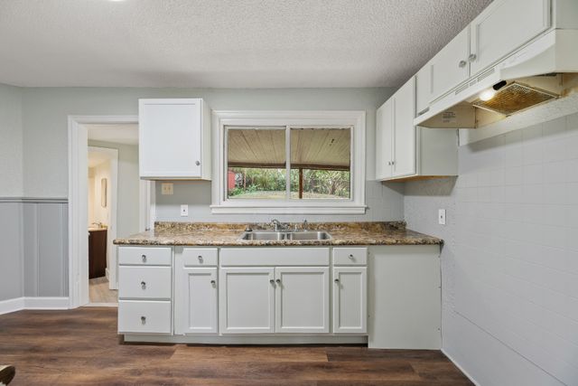 a kitchen with granite countertop a sink cabinets and window