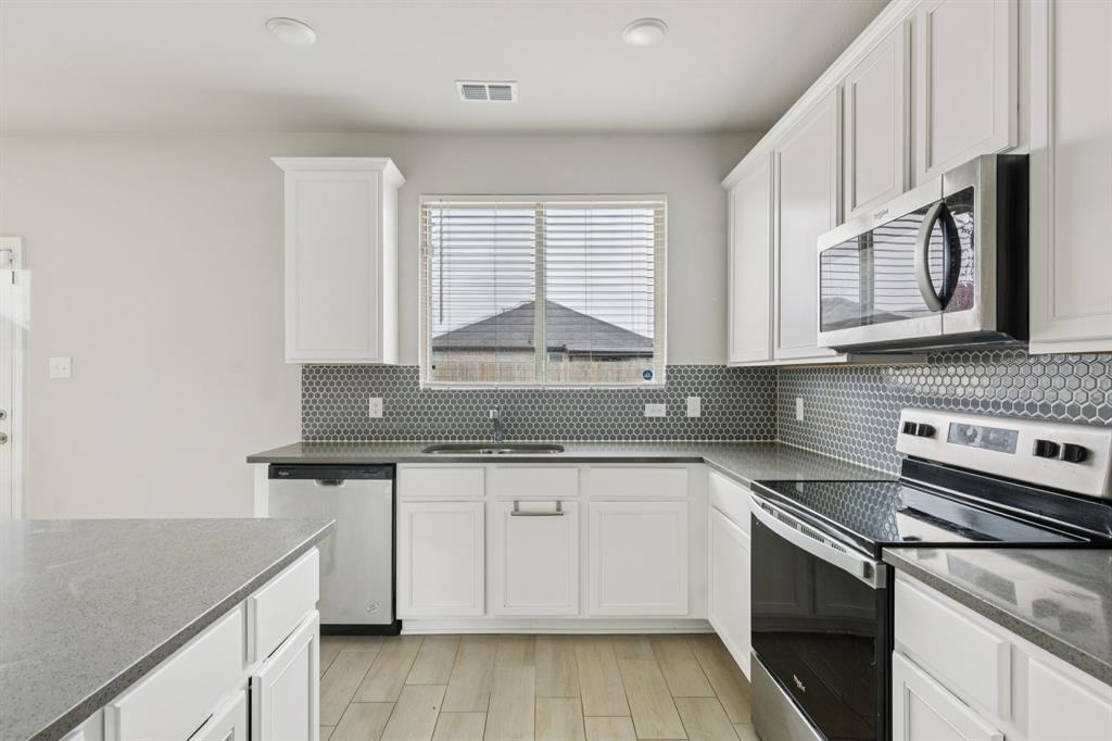 969 Ravenwood Lane Van Alstyne, TX 75495 - Photo 10 of 27 a kitchen with stainless steel appliances granite countertop a sink stove and cabinets