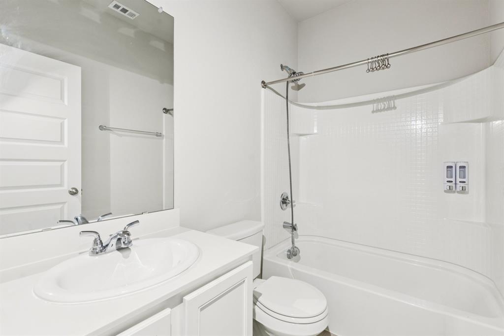 969 Ravenwood Lane Van Alstyne, TX 75495 - Photo 21 of 27 a bathroom with a bathtub shower sink vanity and toilet