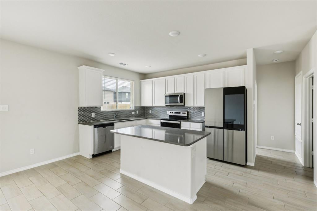 969 Ravenwood Lane Van Alstyne, TX 75495 - Photo 8 of 27 a kitchen with stainless steel appliances a sink a stove a refrigerator cabinets and a window