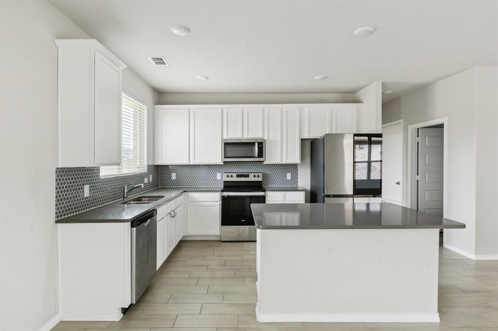 969 Ravenwood Lane Van Alstyne, TX 75495 - Photo 9 of 27 a large kitchen with stainless steel appliances granite countertop a stove a sink and a refrigerator