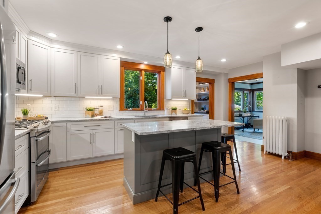 98 Hillside Avenue Arlington, MA 02476 - Photo 14 of 36 a kitchen with stainless steel appliances granite countertop a stove top oven a sink a dining table and chairs