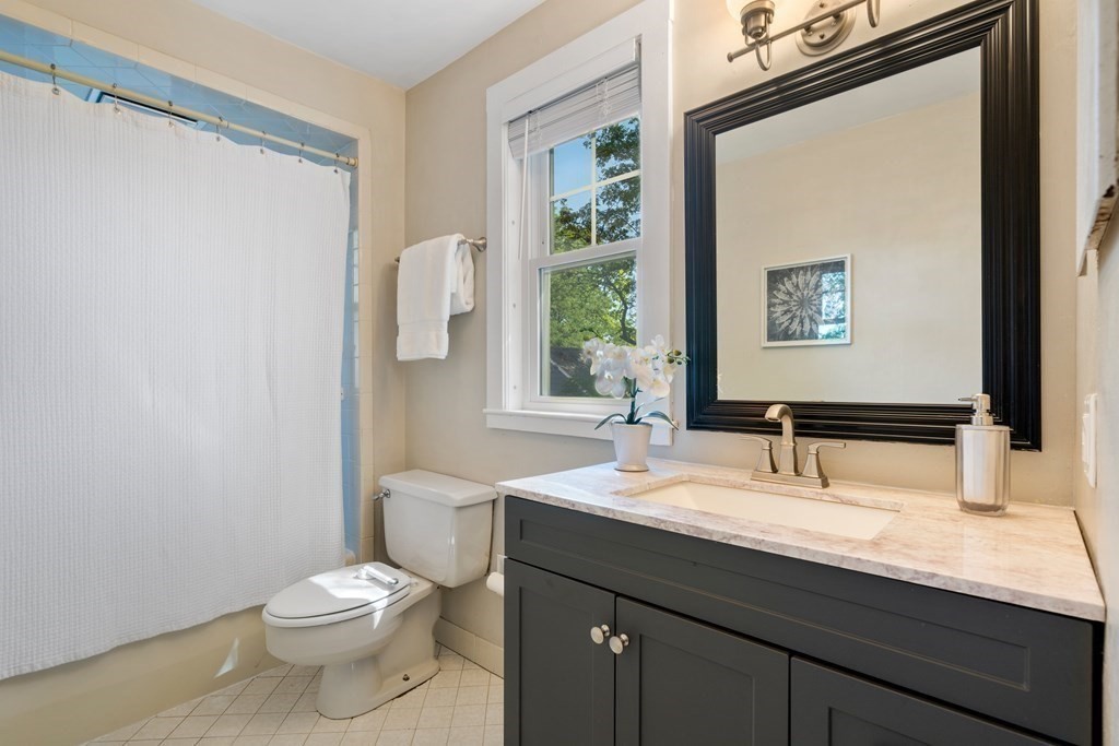 98 Hillside Avenue Arlington, MA 02476 - Photo 26 of 36 a bathroom with a granite countertop sink toilet and mirror
