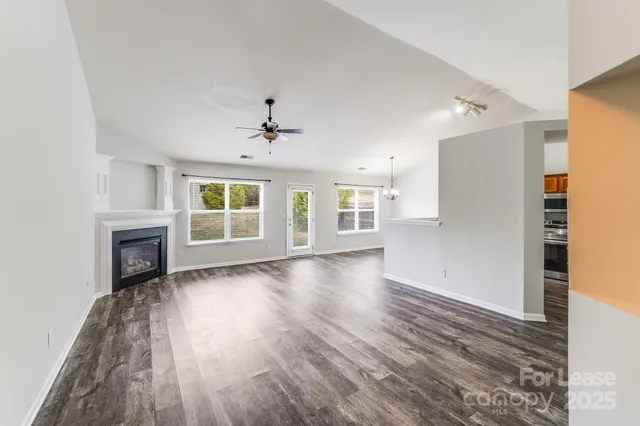a view of an empty room with wooden floor fireplace and a window