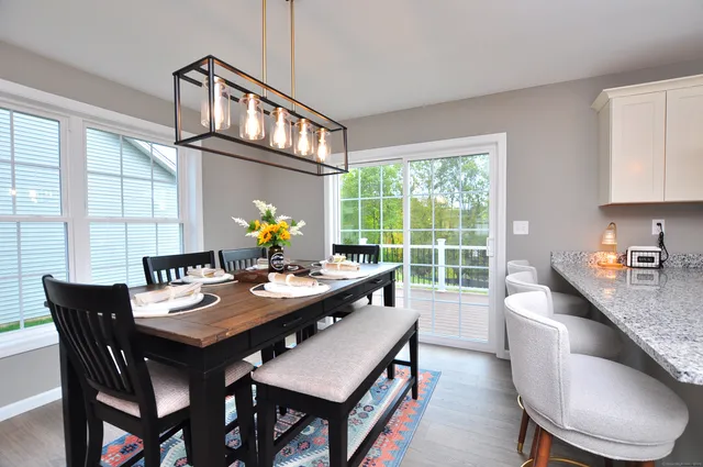 a open dining room with furniture a chandelier and wooden floor
