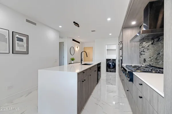 a large kitchen with stainless steel appliances a sink and cabinets