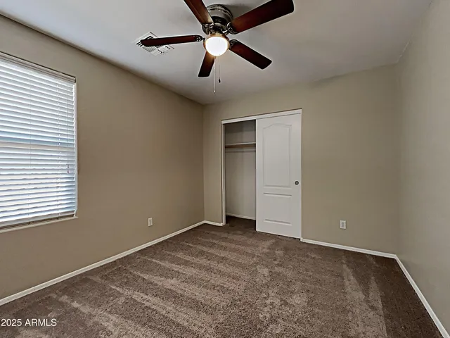 an empty room with windows and ceiling fan