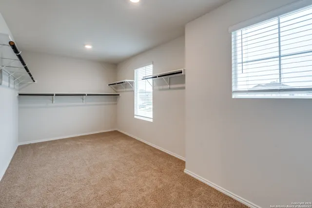 an empty room with windows and refrigerator