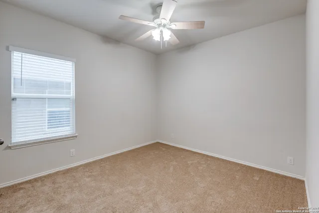 an empty room with a window and a fan