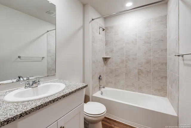 a bathroom with a granite countertop sink a toilet and shower
