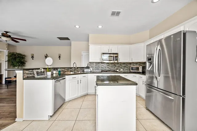 a kitchen with stainless steel appliances granite countertop a refrigerator sink stove and white cabinets