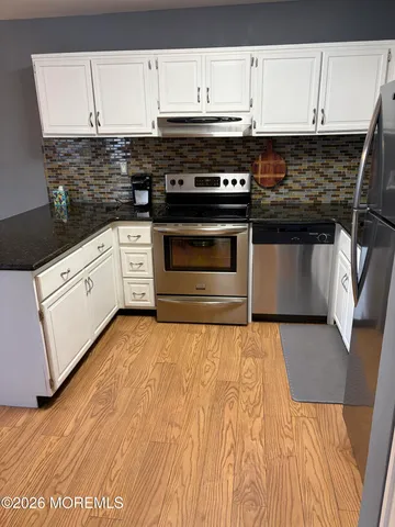 a kitchen with granite countertop a stove and white cabinets