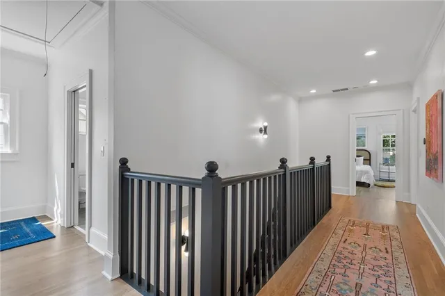 a view of a hallway with wooden floor and a bathroom