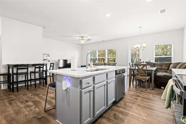 a kitchen with kitchen island a dining table chairs sink and cabinets