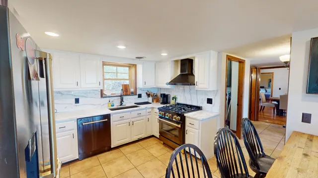 a kitchen with stainless steel appliances granite countertop a sink stove refrigerator and cabinets