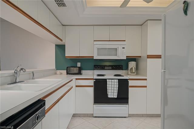 4120 Lorene Drive, Unit 101 Estero, FL 33928 - Photo 10 of 45 a kitchen with stainless steel appliances a stove and white cabinets