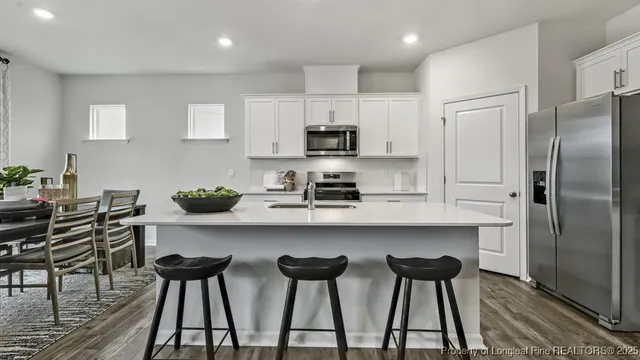 a kitchen with stainless steel appliances a table chairs refrigerator and microwave