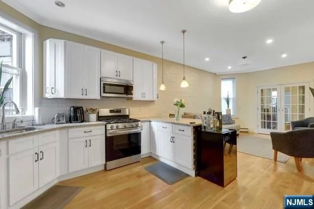 a kitchen with stainless steel appliances granite countertop a stove top oven a sink dishwasher a dining table and chairs with wooden floor