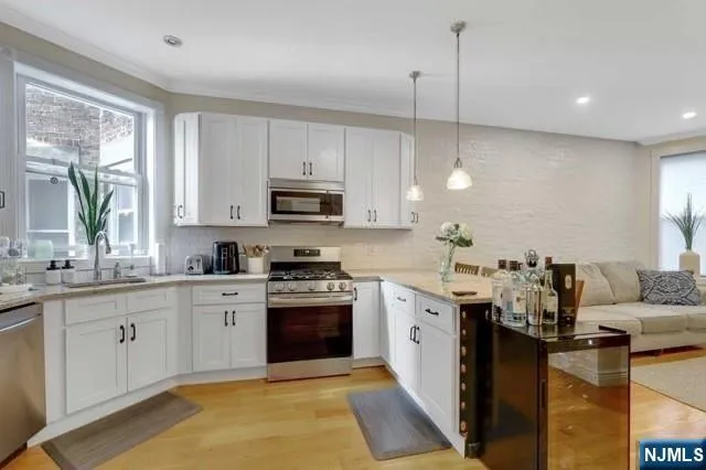 a kitchen with stainless steel appliances granite countertop a sink a stove top oven a chimney a counter space and a window