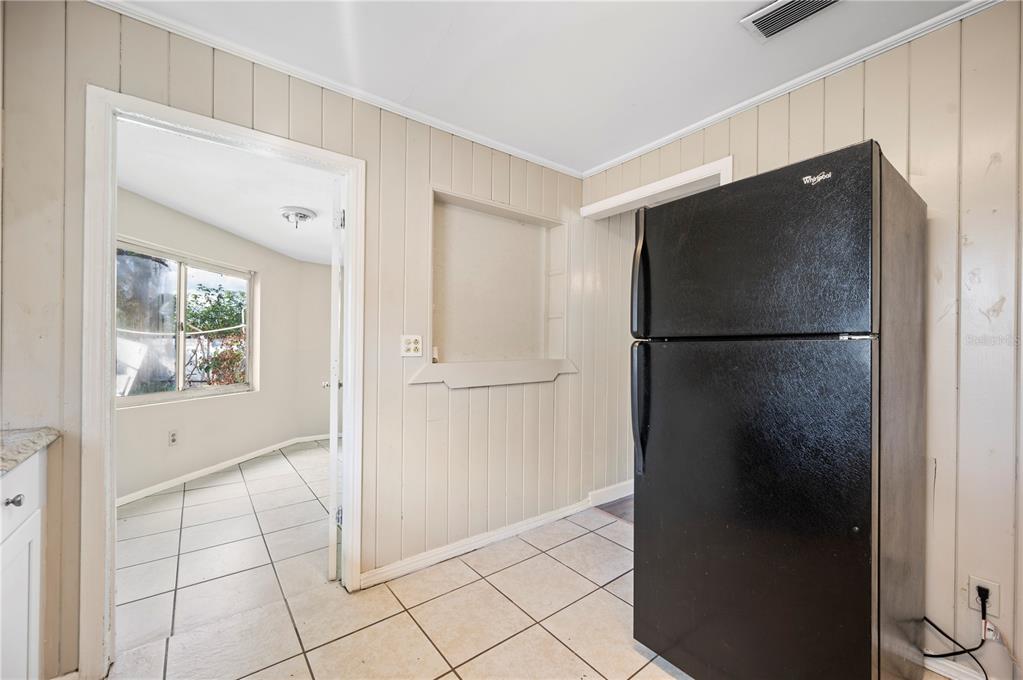 3221 Crutchfield Road Lakeland, FL 33805 - Photo 21 of 49 a view of a refrigerator in kitchen and an empty room in wooden floor