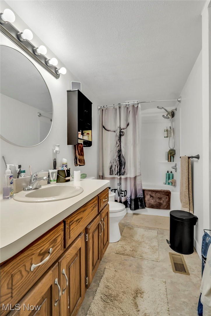 2131 Gordon Road Northwest Dover, OH 44622 - Photo 6 of 25 Full bathroom featuring shower / tub combo with curtain, vanity, toilet, and a textured ceiling