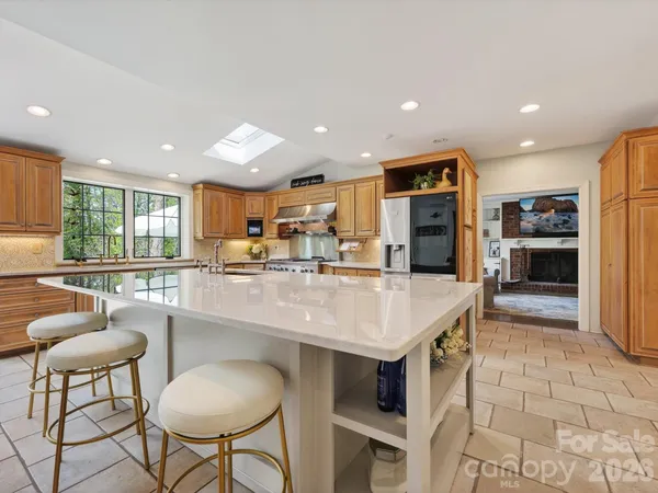 a kitchen with stainless steel appliances kitchen island granite countertop a sink and a refrigerator