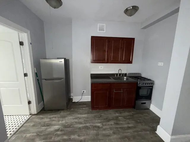 a view of kitchen with granite countertop cabinets and refrigerator