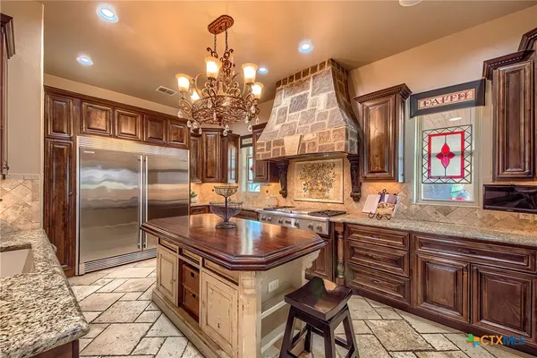 a kitchen with stainless steel appliances granite countertop a sink and a refrigerator