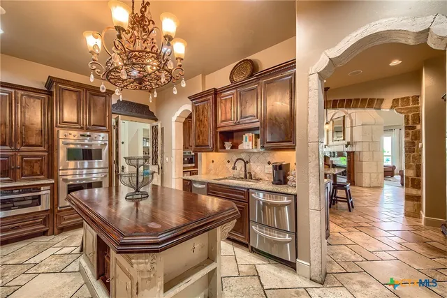 a kitchen with stainless steel appliances granite countertop a sink refrigerator and cabinets
