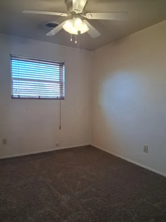 an empty room with a window and a fan