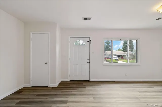 a view of an empty room with wooden floor and a window